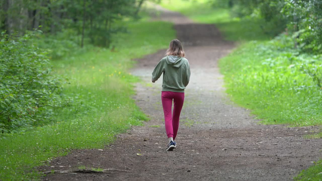 女性健身教练在夏季运动训练期间沿着公园人行道行走的全景图视频下载