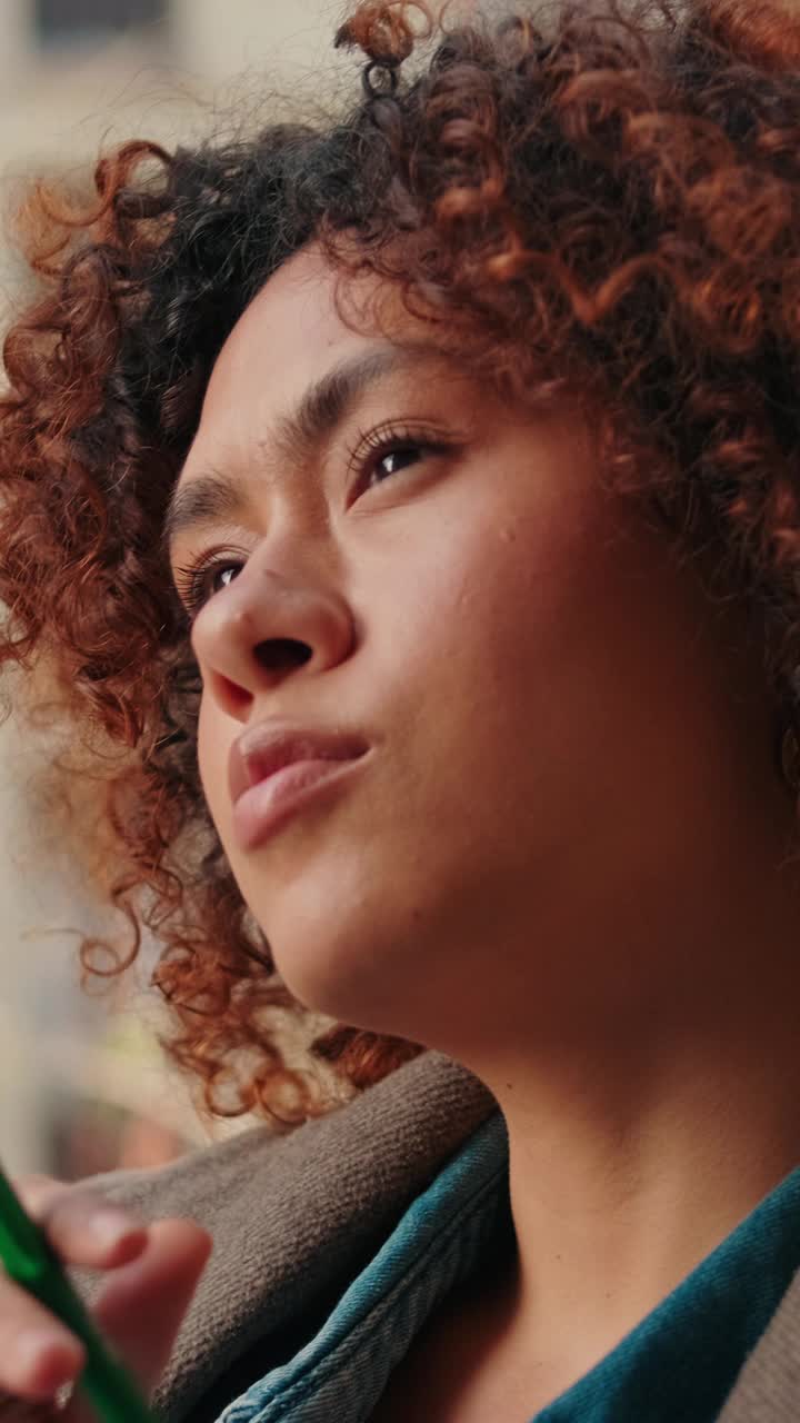 一个沉思的女人坐在阳台上，手里拿着笔视频素材