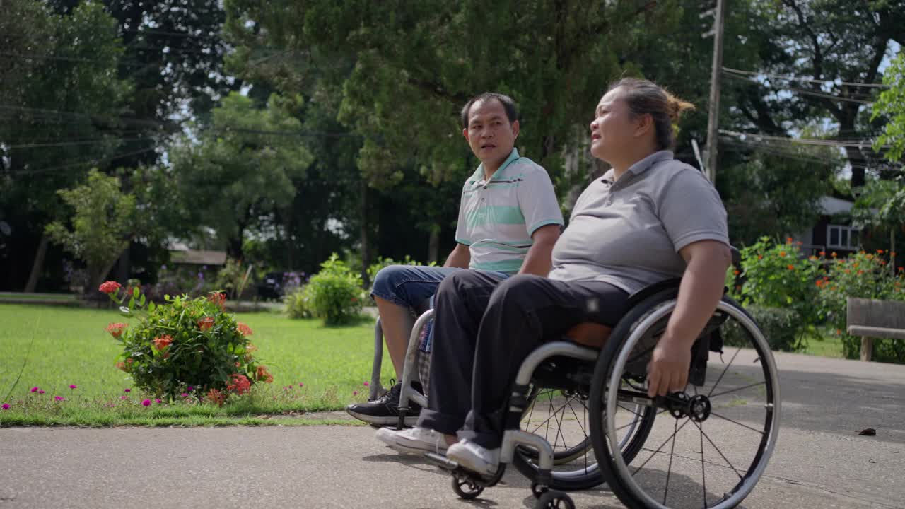 在一个阳光明媚的日子里，坐轮椅的夫妇喜欢在外面聊天，互相陪伴视频素材