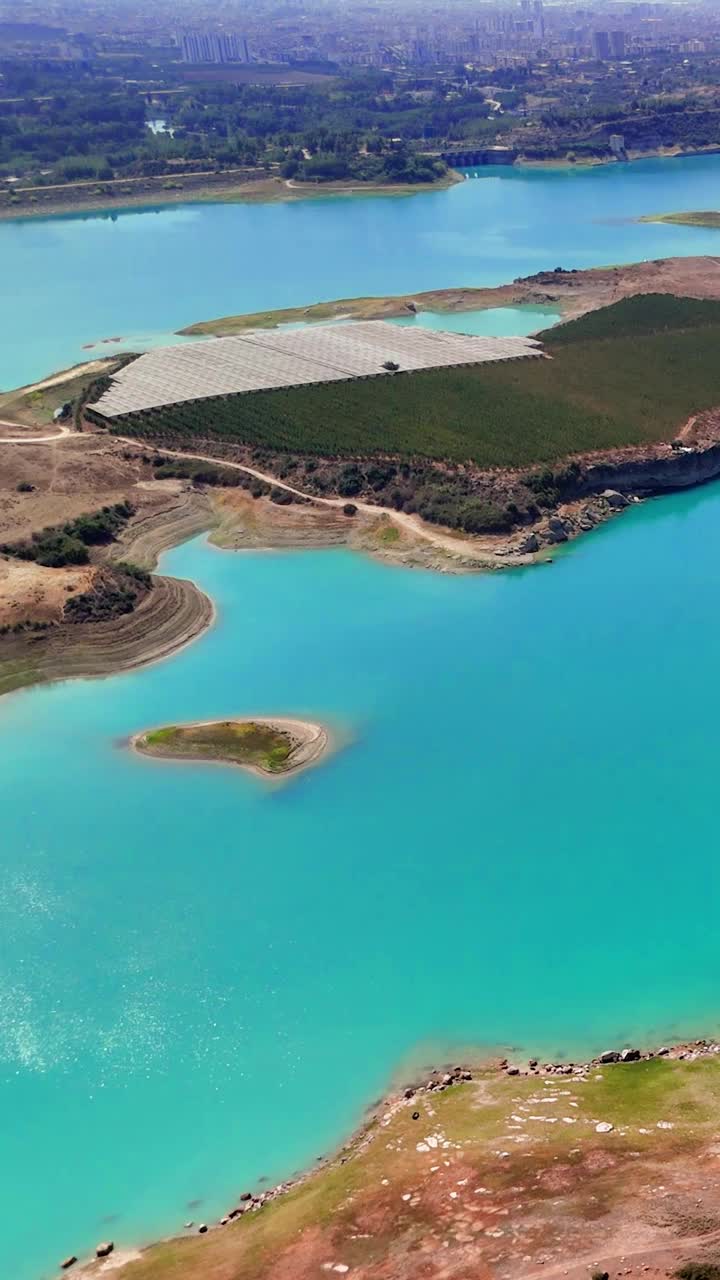 绿松石般的海水在阳光下闪烁，海岸线上点缀着温室。城市的天际线在远处冉冉升起，形成了令人惊叹的城市背景视频下载