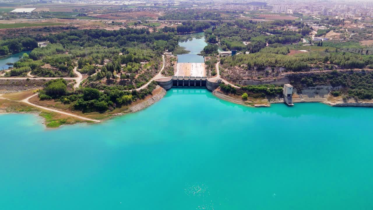 空中镜头翱翔在风景秀丽的大坝和水库，展示了充满活力的绿松石水和郁郁葱葱的绿色植物视频下载