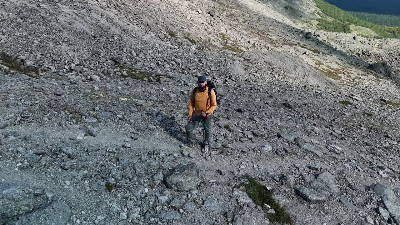 鸟瞰图上的男性徒步旅行者在岩石坡的山手势胜利的标志视频素材