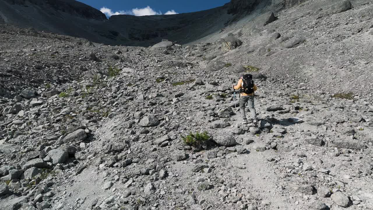 男徒步旅行者沿着布满岩石的小路走到山顶视频素材