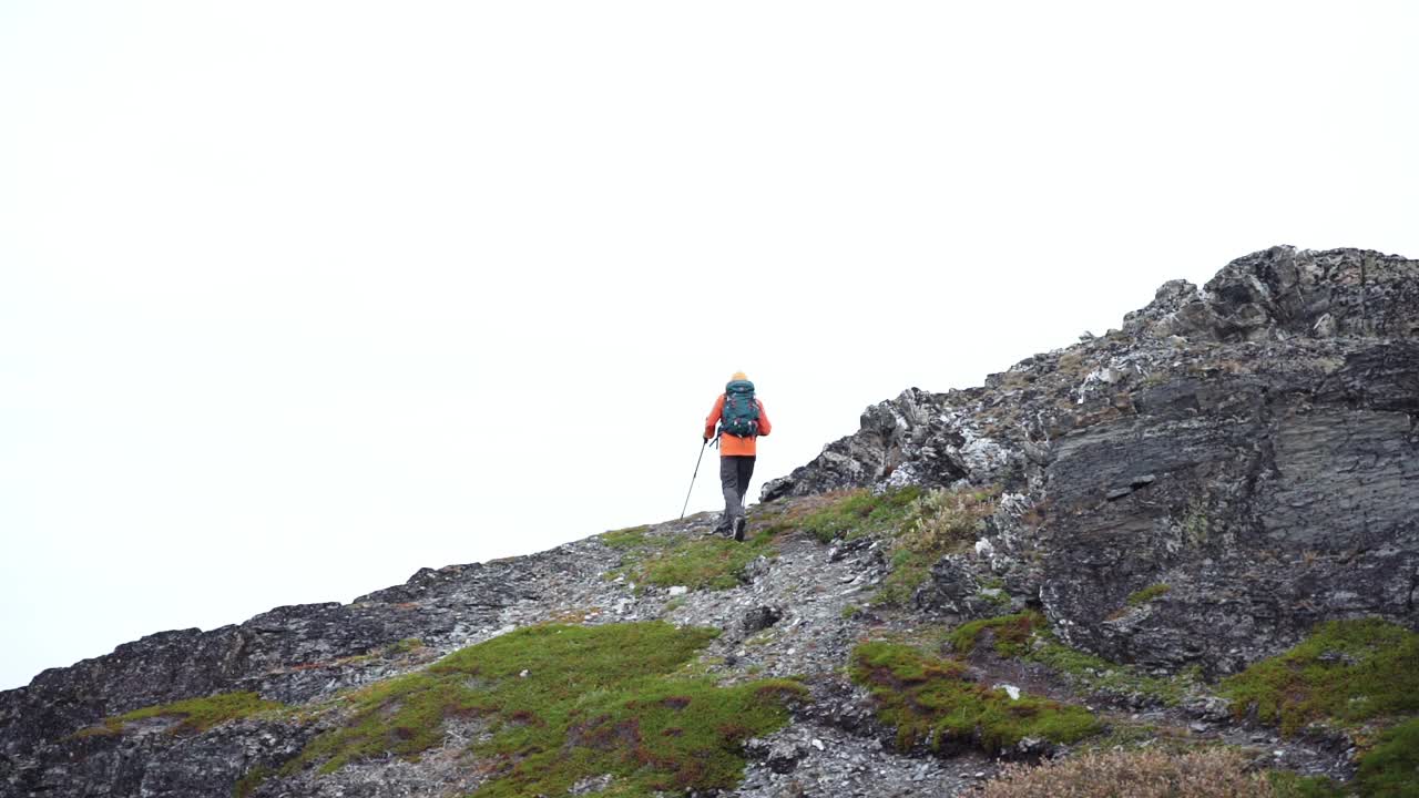 一名男子背着背包和登山杖走上山顶视频素材