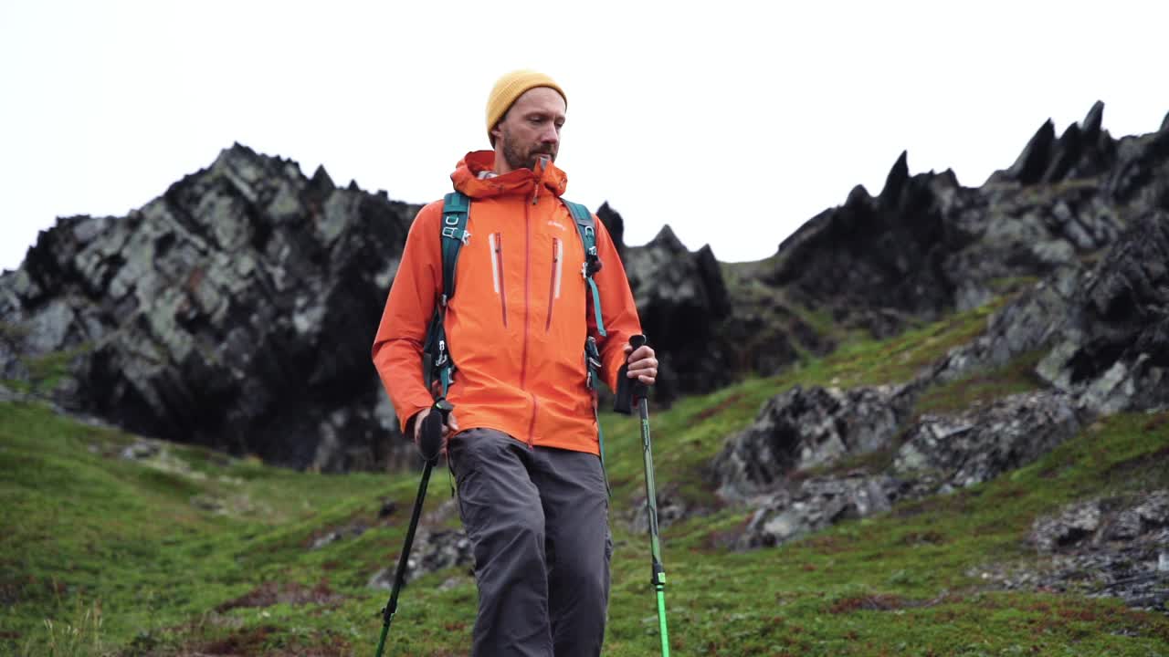 男徒步者背着背包和登山杖在山上行走视频素材