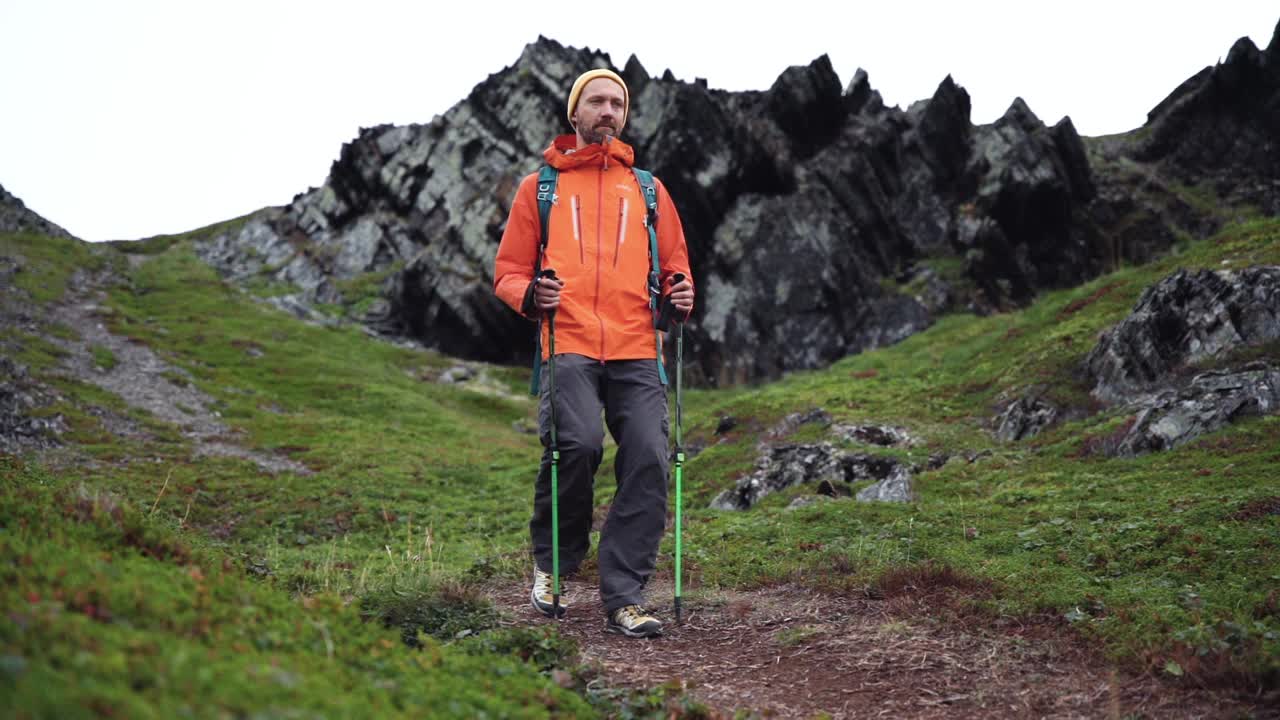 男徒步者背着背包和登山杖在山上行走视频素材