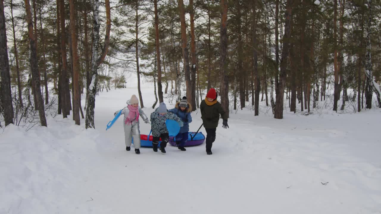 快乐的孩子们在冬天用雪管和雪碟跑上山视频下载