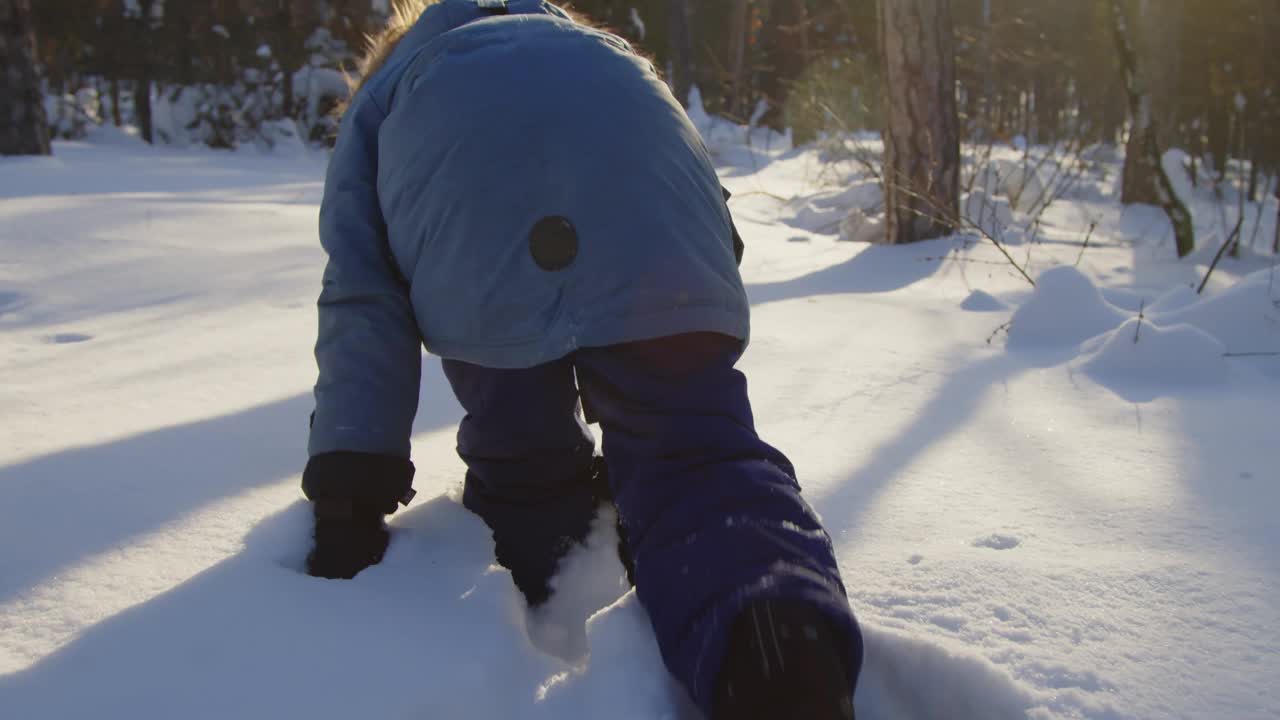 男孩在森林里走过雪堆和扔雪视频素材