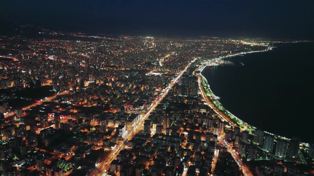 夜幕降临时，沿海城市灯火通明，展现出充满活力的天际线。汽车行驶在灯火通明的高速公路上，增强了海岸和城市景观的美感视频素材