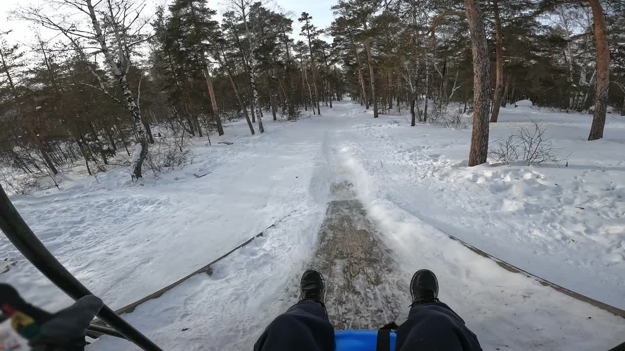 在冬季森林的雪管上滑下冰道和山坡的视角视频下载