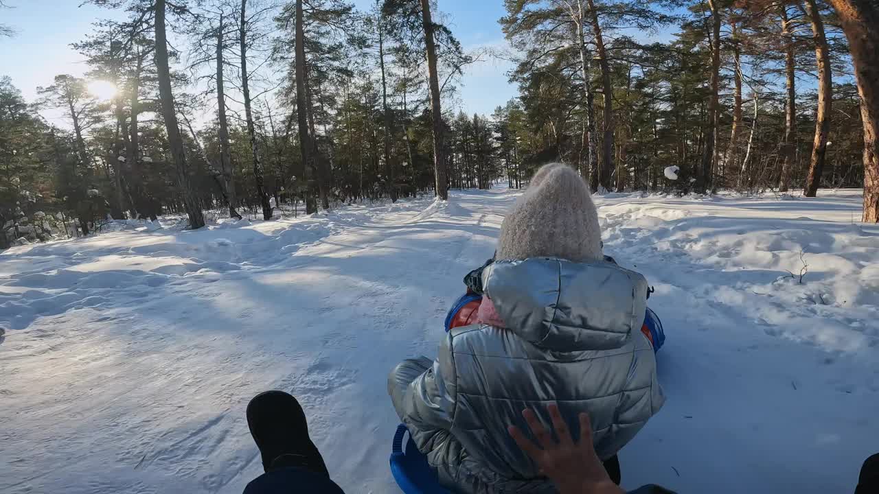 与朋友在冬季森林中的雪地管道的POV视频下载