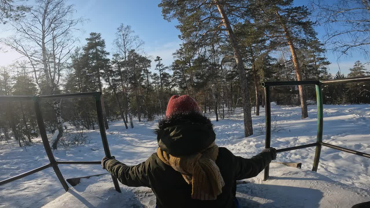 与朋友在冬季森林的雪管上滑下山坡的镜头视频下载