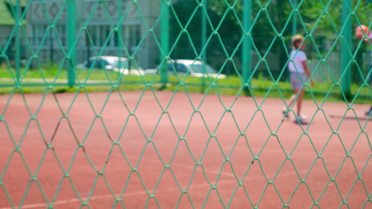 一个女孩在公园的室外场地弹跳篮球。孩子在爸爸的关怀下练习打篮球。运动休闲和周末。家庭时间。篮球比赛视频素材