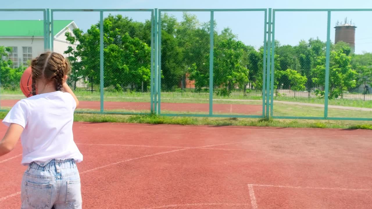 在城市的球场上练习打篮球的小女孩。视频下载