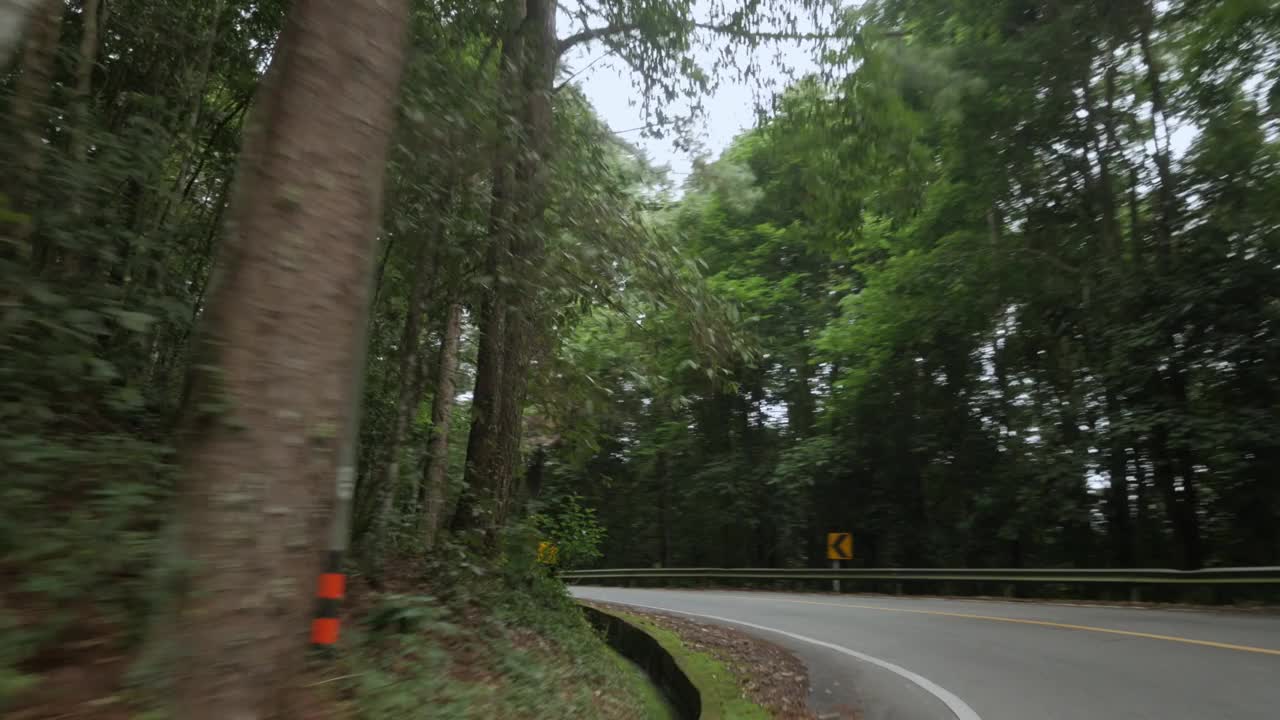 上午，泰国北部山区的乡村小路穿过雨林，前方摄像头拍摄穿过山路的移动汽车视频下载