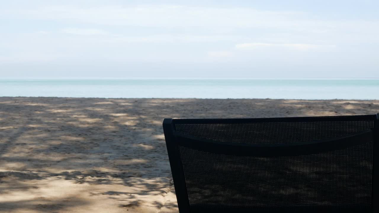 夏日阳光明媚的日子，蔚蓝的天空，沙滩躺椅上的白色沙滩海景景观视频下载