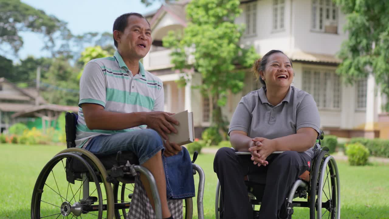 幸福的轮椅使用者夫妇，丈夫和妻子，享受着彼此的陪伴，微笑和笑声，在一个阳光明媚的日子里在外面放松视频下载