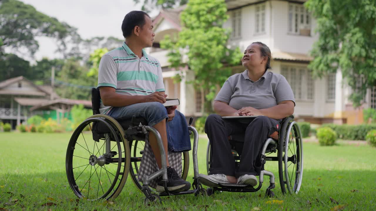 幸福的轮椅使用者夫妇，丈夫和妻子，享受着彼此的陪伴，微笑和笑声，在一个阳光明媚的日子里在外面放松视频素材