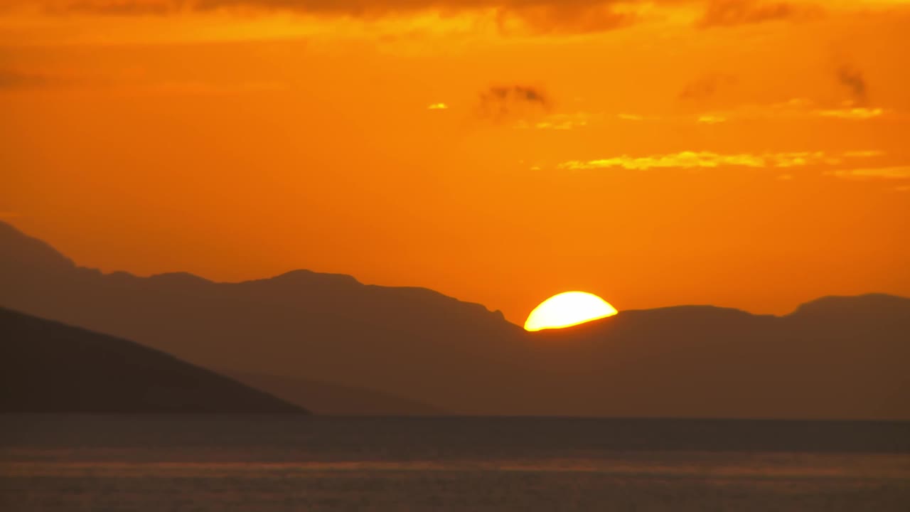 夕阳落在山后，橙色的天空和大海视频下载