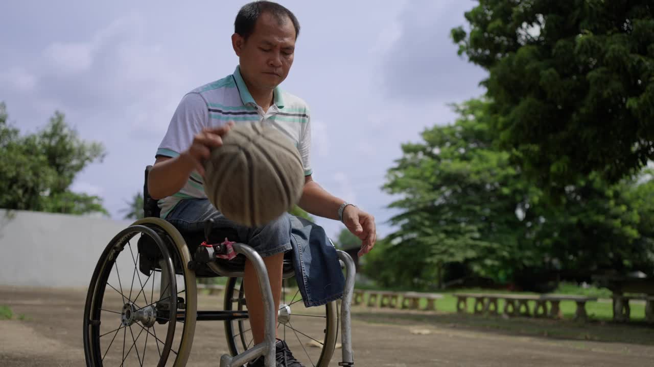 快乐的轮椅使用者在一个阳光明媚的日子里练习运球和投篮视频下载