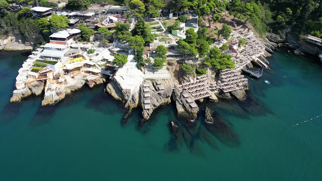 在一个阳光明媚的夏日，鸟瞰位于地中海沿岸风景如画的裂缝岩石上的海滩视频素材