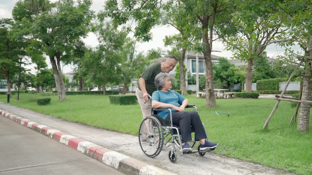 当年迈的妻子在公园里休息时，丈夫帮她推轮椅。视频下载