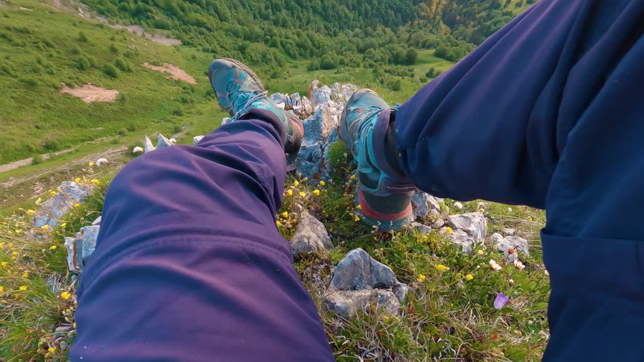 一个徒步旅行者坐在山崖边的双腿的第一人称视角视频素材