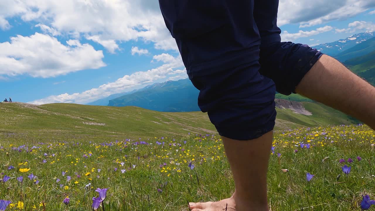 一个人赤脚走在山上的草地和鲜花上视频素材