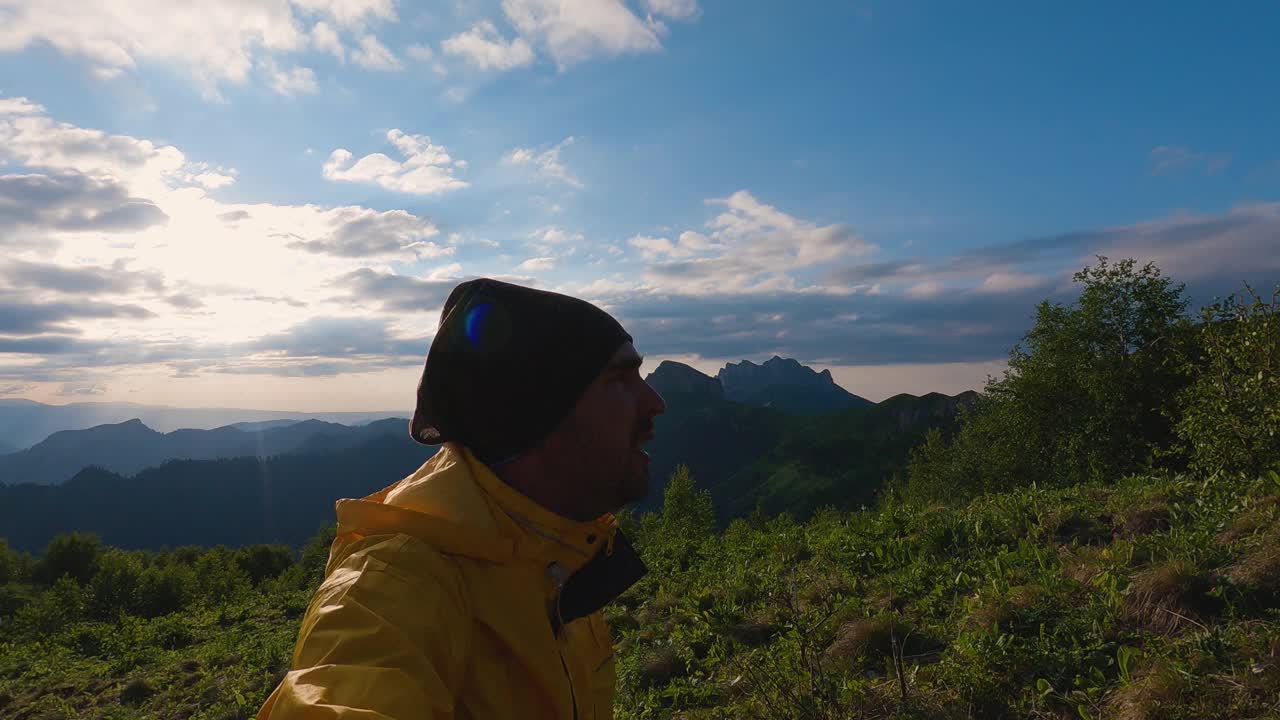 游客穿着黄色的风衣，在落日的背景下走在山上视频下载