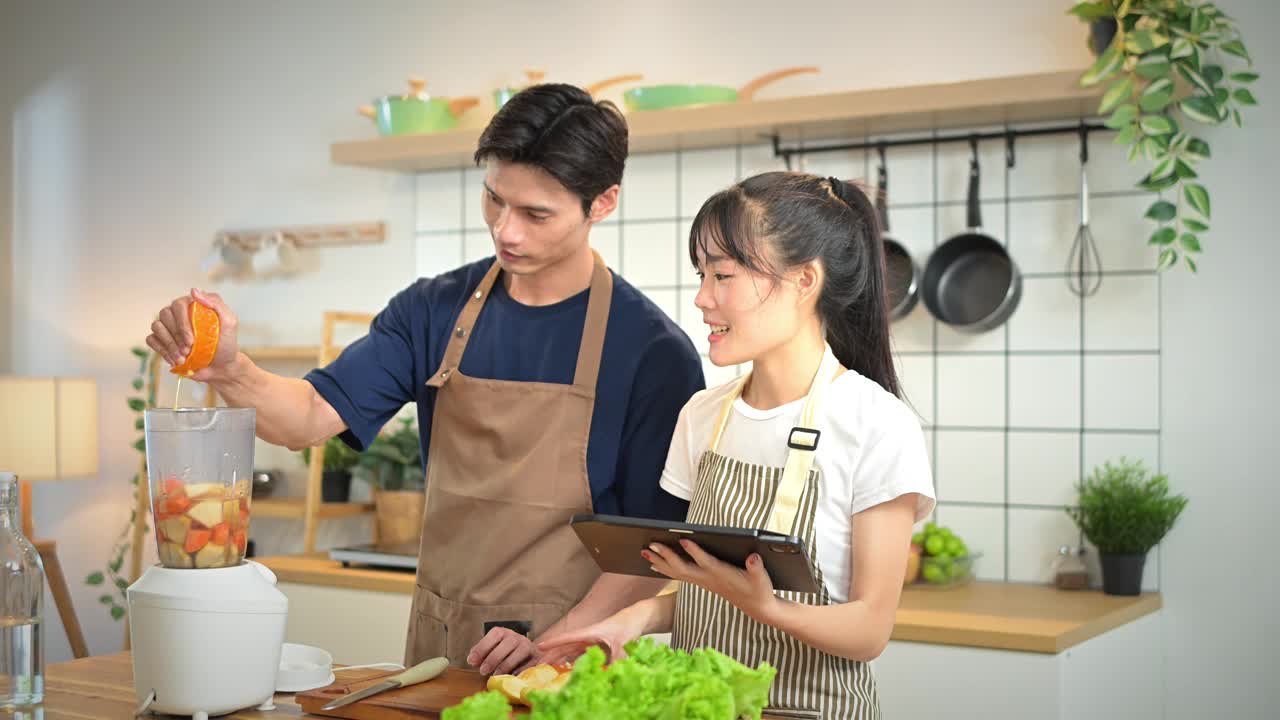 幸福美丽的年轻夫妇在他们现代化的厨房里准备了一杯健康的饮料。视频下载