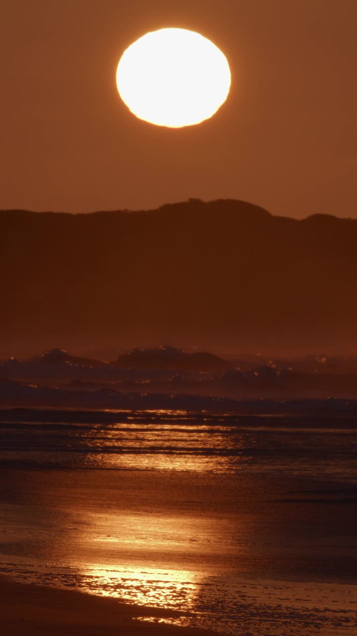 黎明的海浪在金色的日出中破碎。视频素材