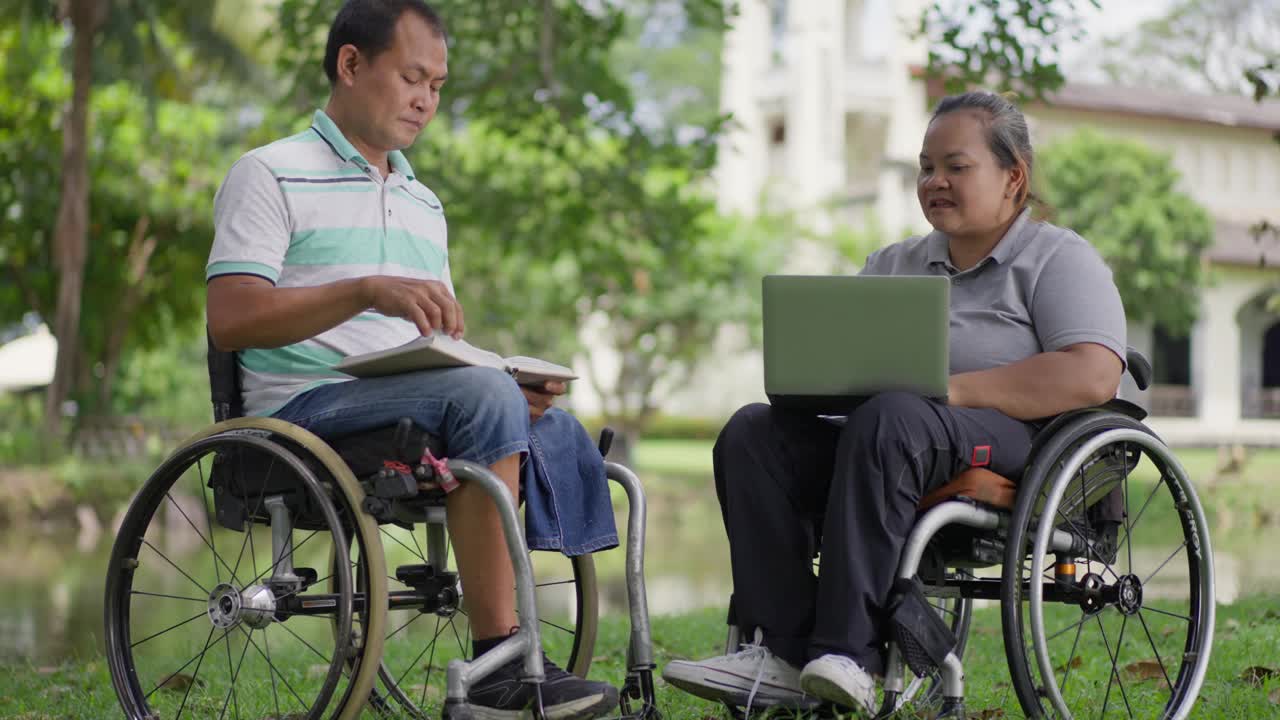 两个轮椅使用者，丈夫和妻子，在一个阳光明媚的日子里呆在外面工作和阅读视频素材