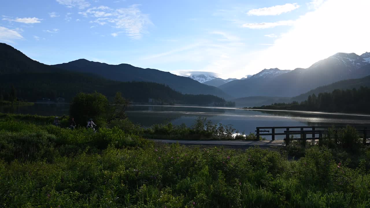 朋友们沿着指定的自行车道骑自行车，可以看到湖和山视频素材