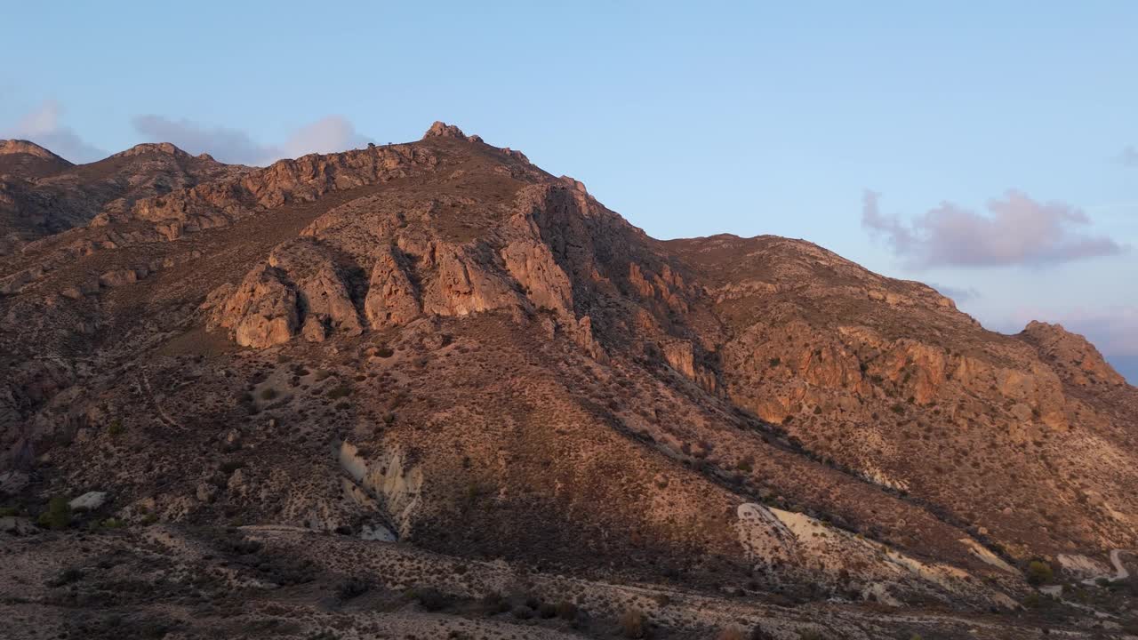 空中飞行。在蓝天下，阴影在沙漠山脉上慢慢移动。鸟瞰美丽的山景视频下载