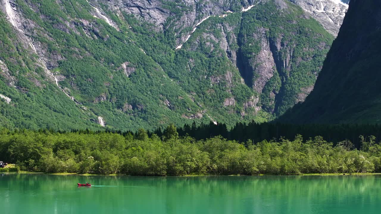 在挪威峡湾宁静的绿色水域划皮艇，周围环绕着雄伟的山脉视频下载