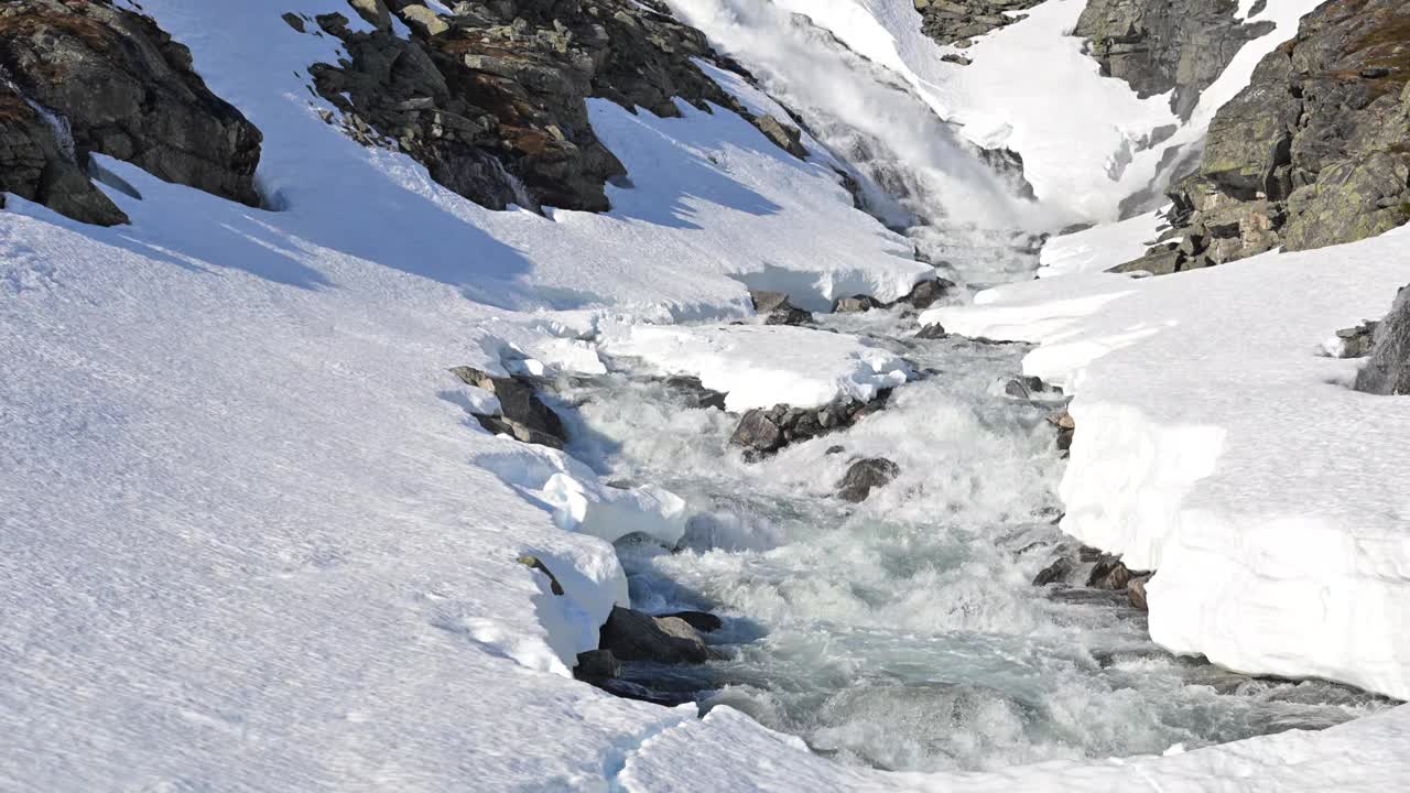 春天，在宁静的阿尔卑斯山谷里，雪山溪流流淌着融化的雪视频下载