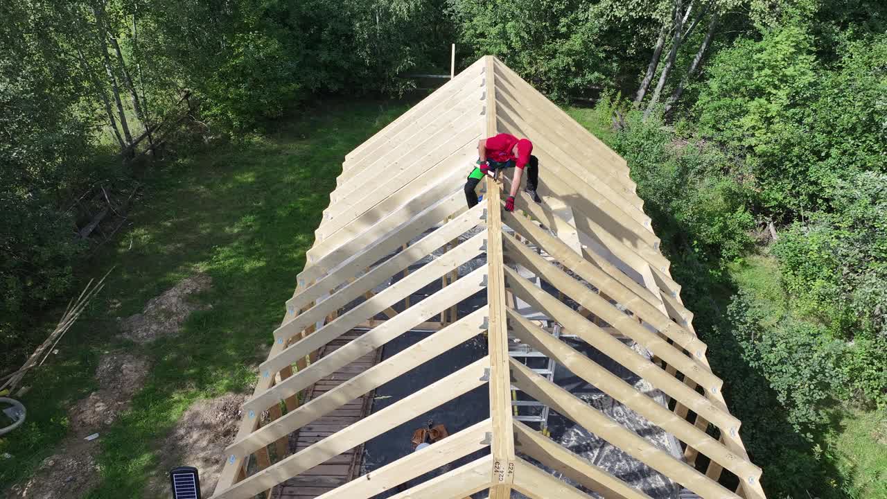 夏季，建筑商在宁静的树林中建造木制屋顶框架视频下载