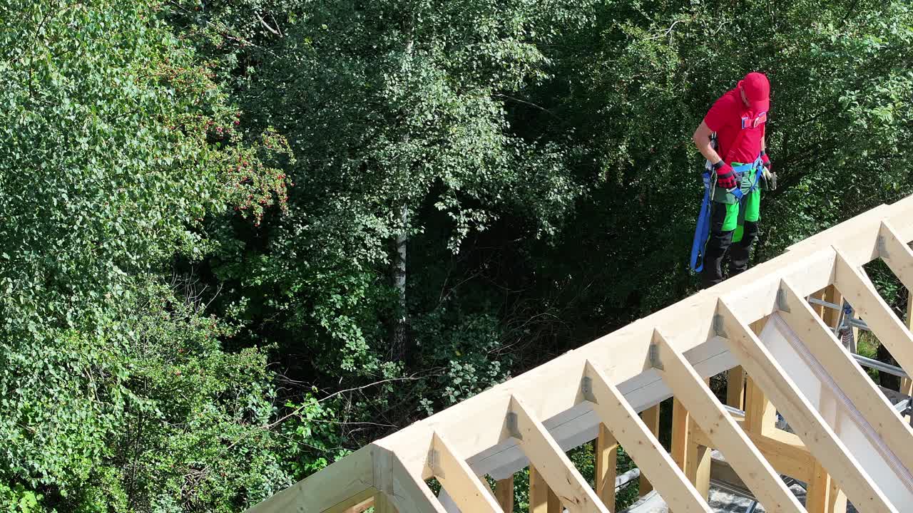 建筑工人白天在森林地区的屋顶结构上保持平衡视频下载