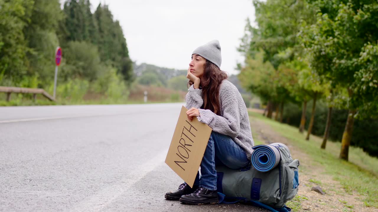 年轻的背包旅行者在路边等待。视频下载