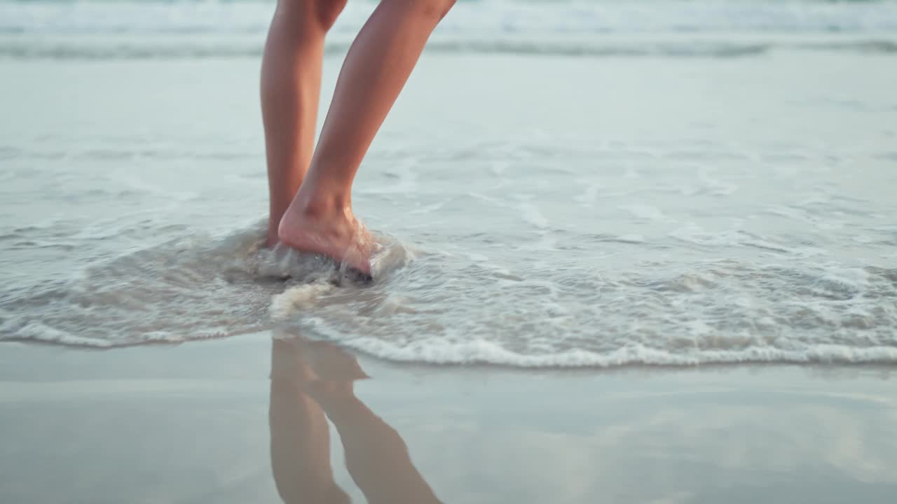 B滚——沙滩上沿着海浪行走的女人的脚，夏季旅游假期的女游客，慢动作视频下载