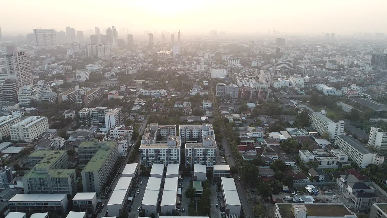 鸟瞰现代化的办公大楼和村庄，清晨的太阳升起曼谷大都市视频素材