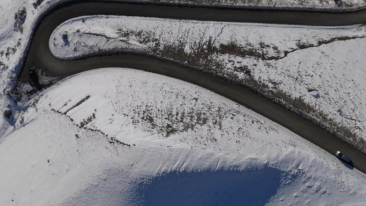 汽车小心翼翼地行驶在被雪包围的蜿蜒道路上视频素材