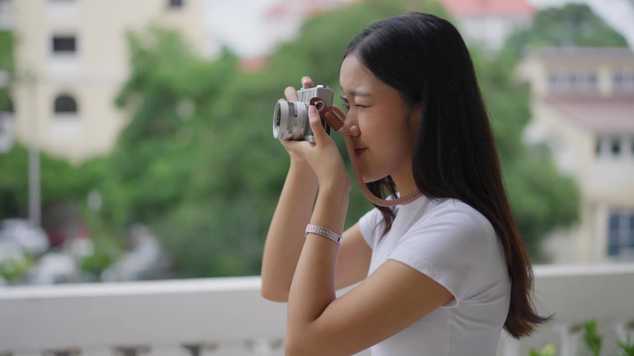 快乐的年轻女游客正在用她的胶片相机拍摄她正在参观的地方视频下载