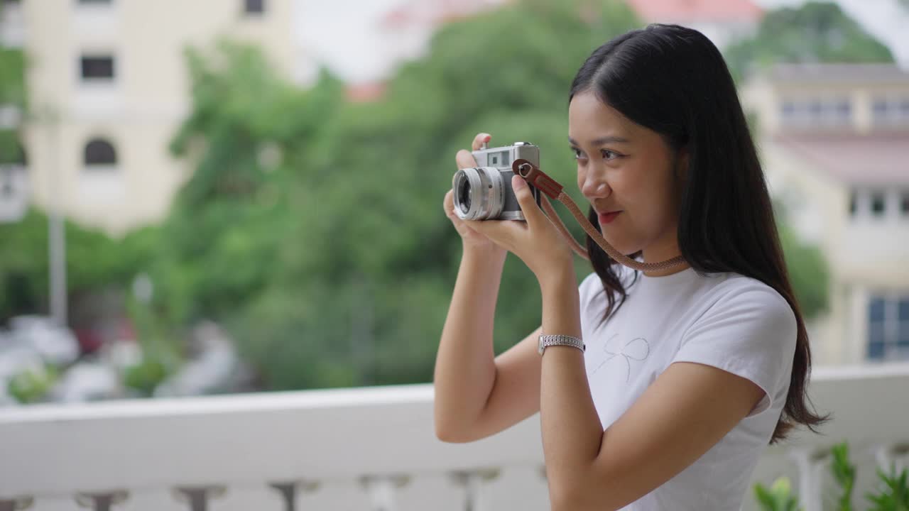 快乐的年轻女游客正在用她的胶片相机拍摄她正在参观的地方视频下载