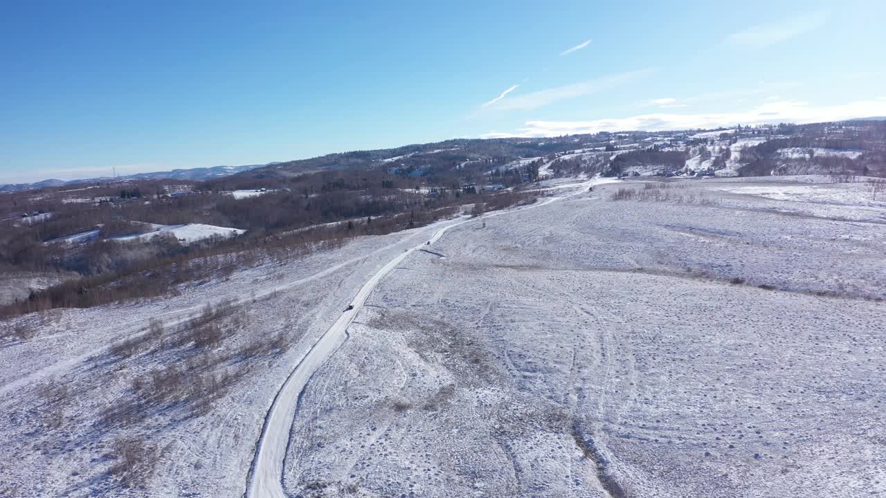 一辆汽车在冬季道路上行驶的鸟瞰图。冬季乡村景观视频下载