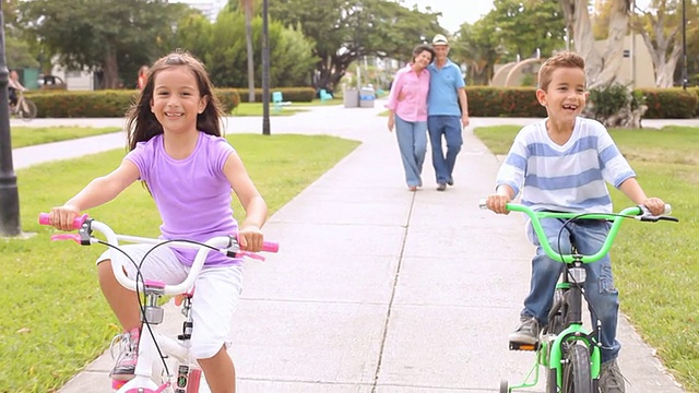 爷爷奶奶带孙子孙女在公园里骑自行车视频素材