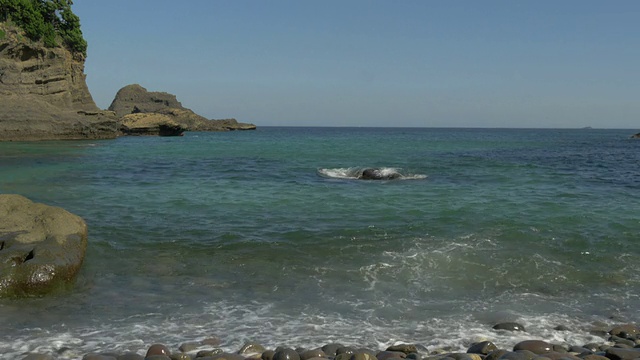 平静而清澈的海浪正在逼近岩石嶙峋的海岸线。视频下载