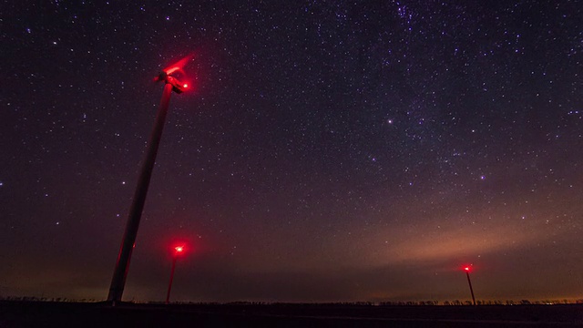 风力涡轮机在夜间发电，以旋转的星空为背景视频素材