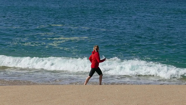 女人在海滩上跑步，海浪在背景中视频素材