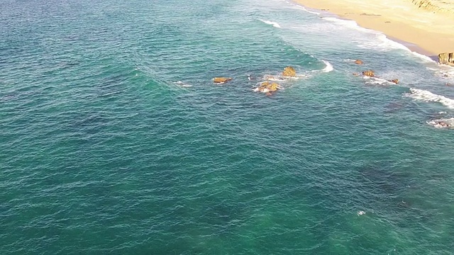 海浪冲击着海滩，鸟瞰图向后移动视频素材